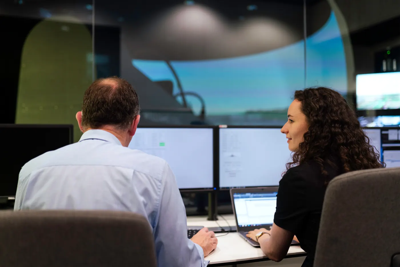Two colleagues working at monitors in an operations room