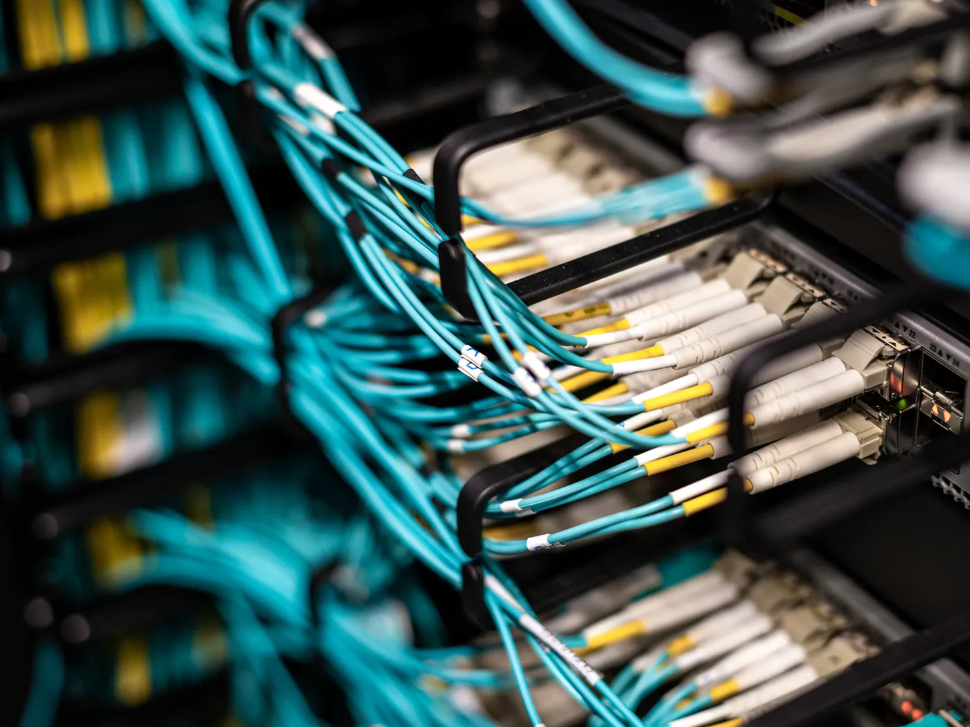 Teal fibre-optic cables connected to a server rack